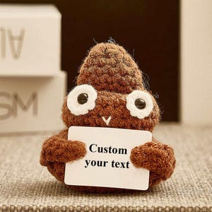 May include: A brown crocheted poop emoji holding a white card that says "Custom your text".