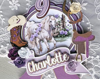 May include: Purple and white cake topper with a white horse, a horseshoe, a cowboy hat, and the number 9. The topper also includes the name Charlotte.
