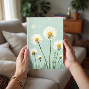 May include: A light blue notebook with a floral design featuring white daisies with yellow centers on a light blue background.