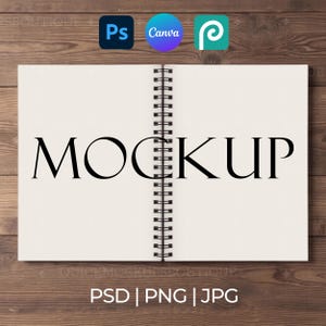 May include: An open spiral-bound notebook with off-white pages featuring the word MOCKUP printed in large black capital letters across the center. The notebook is displayed against a dark brown wood grain background with software icons above.