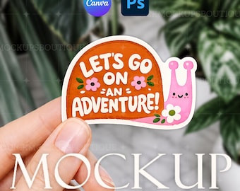 May include: A vibrant sticker with a cartoon snail design and the words "LET'S GO ON AN ADVENTURE!". The snail is pink with a smiling face and a white flower. The sticker has an orange background with pink flowers.