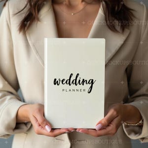 May include: A white planner with the text "wedding planner" in black cursive writing.