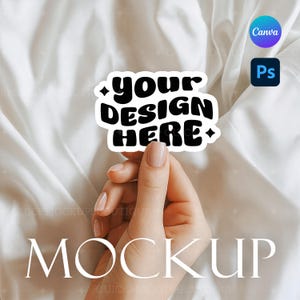 Puede incluir: Una pegatina blanca con el texto "your DESIGN HERE" en negro, sostenida por una mano con uñas cuidadas. La pegatina tiene un borde negro y detalles de estrellas. Los logotipos de Canva y Photoshop son visibles en el fondo.