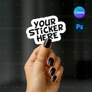 May include: A white sticker with the text "YOUR STICKER HERE" in a black, bold font. The sticker is held by a hand with black nail polish and gold rings. The background is dark gray.