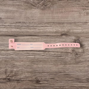 May include: Pink plastic hospital identification bracelet with fields for name, bed, sex, and date.