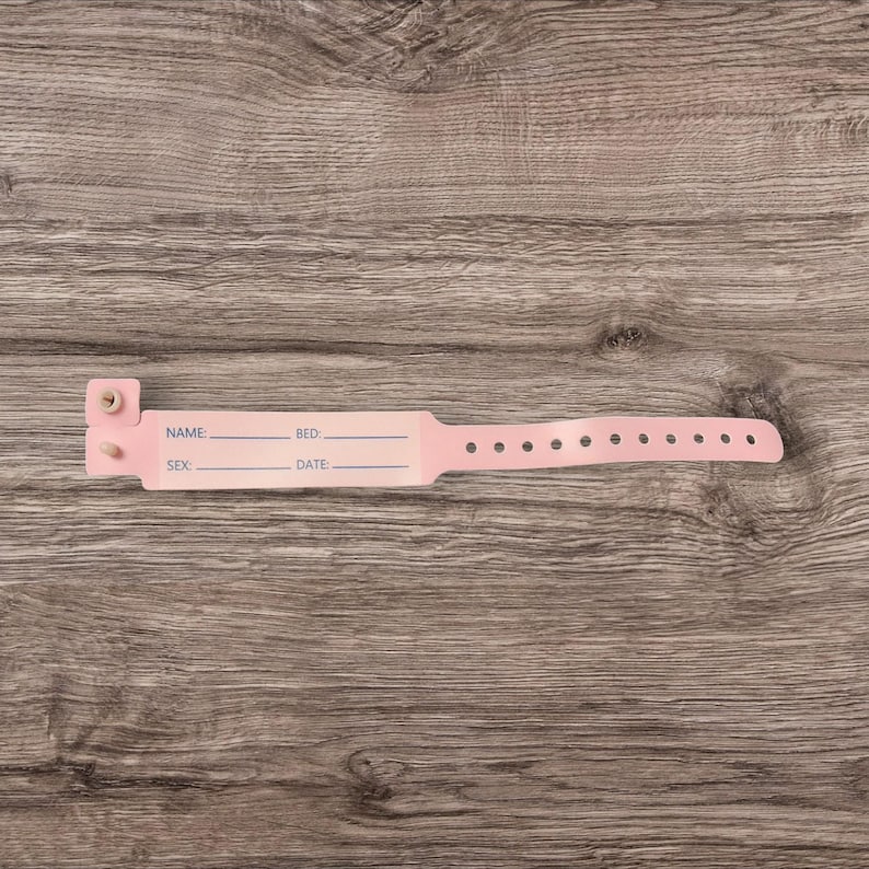 May include: Pink plastic hospital identification bracelet with fields for name, bed, sex, and date.