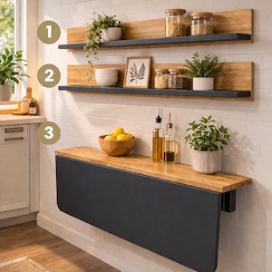 Könnte beinhalten: Ein dreiteiliges Küchenset mit einem Tisch und zwei Regalen. Der Tisch hat eine schwarze Basis und eine Holzplatte mit abgerundeten Ecken. Die Regale sind aus Holz mit schwarzem Rand. Das Set enthält Gläser, Pflanzen und ein gerahmtes Bild.