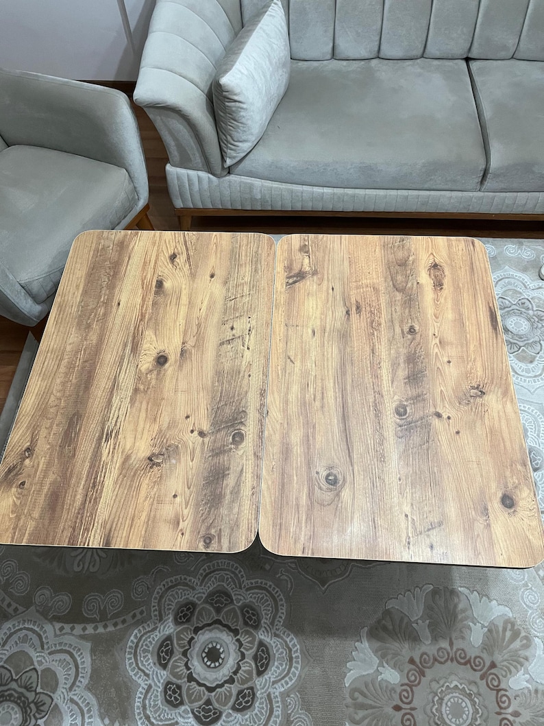 May include: A wooden coffee table with a light brown finish. The table is made of two separate pieces that can be joined together. The table is sitting on a patterned rug.