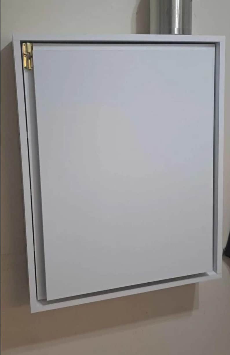 May include: White wall-mounted cabinet with a single door that folds down. The cabinet has a simple design and is made of wood.
