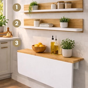 May include: A white and wood-tone table and two-shelf set. The table has a white drop-leaf design with oval corners. The shelves are wood-toned with white ledges. The set includes three pieces, perfect for a kitchen or dining area.