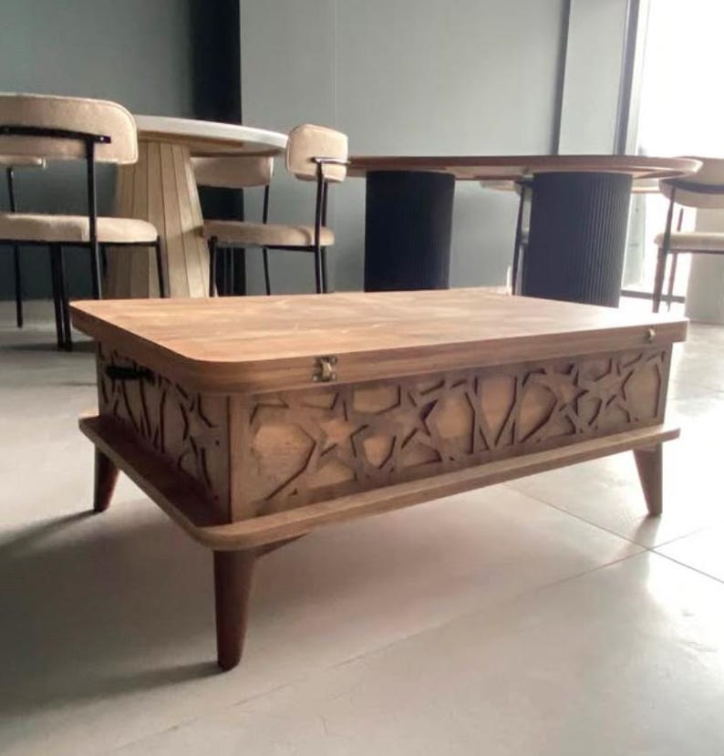 May include: A wooden coffee table with a lift-top lid and intricate star-shaped cutouts. The table has a dark brown finish and sits on four legs.