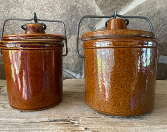 Conjunto vintage de dos (2) vasijas pequeñas de mantequilla/queso con tapa de bloqueo Crock rústico de principios de siglo para decoración de granja Rootbeer Brown Glaze Metal