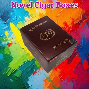 May include: A dark brown cigar box with gold lettering and the text "Novel Cigar Boxes." The box features the words "La Flor Dominicana" and "Double Ligero." The background is a colorful abstract painting.
