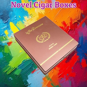 May include: A brown cigar box with gold lettering and accents. The box has the text "La Flor Dominicana" and "ORO CHISEL TUBO". The top of the box has a gold emblem. The words "Novel Cigar Boxes" are at the top.