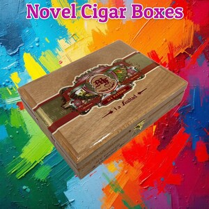 May include: A rectangular wooden cigar box with a polished finish, featuring a decorative label with the text My Father and La Lealtad. The box has a gold-colored metal latch on the front edge and a detailed graphic design on the lid.