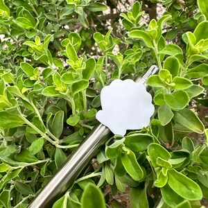 May include: A silver metal pen with a white paper sticker attached to the top. The sticker is shaped like a cloud and has a smooth, blank surface.
