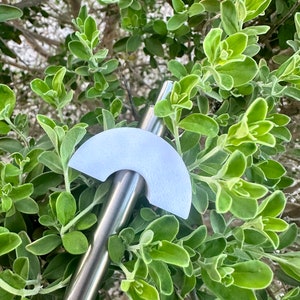 May include: A light blue, half-circle shaped reusable straw topper. The topper is made of a smooth, matte material and is attached to a stainless steel straw.