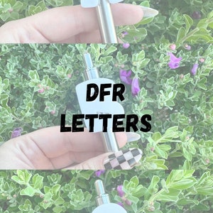 May include: Three silver vape pens with white letter attachments. The letters are A, B, and C. The pens are in a hand against a green leafy background.
