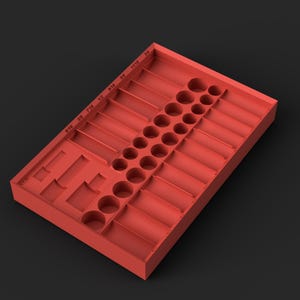 Puede incluir: Una bandeja organizadora rectangular de color rojo con múltiples compartimentos circulares y rectangulares para almacenar herramientas. La bandeja incluye medidas imperiales impresas que van de 5/16 a 3/4 de pulgada a lo largo del borde superior.