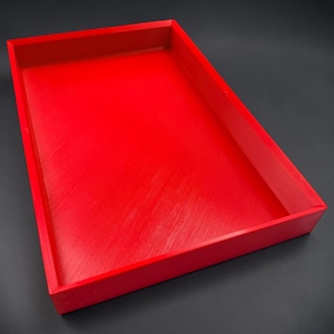 May include: A rectangular tray with a vibrant red finish and raised edges. The interior surface features a subtle, diagonal textured pattern across the base, while the exterior walls are smooth and solid, forming a clean, open-top container.