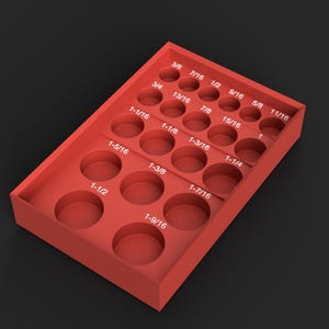 May include: A red rectangular storage tray featuring multiple circular cutouts for organising tools. Each slot is labelled with white text indicating imperial measurements ranging from 3/8 to 1-9/16 inches, arranged in a grid pattern for sorting.