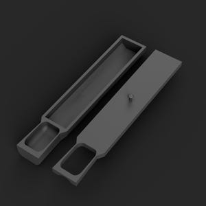 May include: A matte black rectangular storage tray with a long, narrow open compartment and a smaller rounded square section. A matching rectangular lid with a small central knob is positioned beside the tray, featuring a cutout handle.