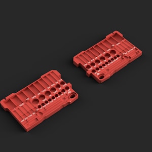 May include: Two rectangular red drill bit organizers featuring multiple circular slots and molded channels. Each organizer is labeled with white printed fractional inch measurements ranging from 9/32 to 1 inch, designed for sorting and storing drill bits.