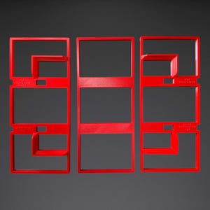 May include: Three bright red rectangular plastic cookie cutters with open centres. The left and right cutters feature internal L-shaped dividers and embossed text reading "MOUNTAINEER MAKES" and "BAUER STYLE V1.0" on the frame edges.