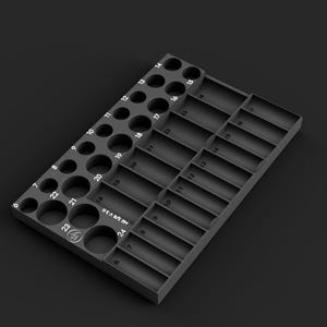 May include: A matte black rectangular tool organizer tray featuring a grid of circular and rectangular slots. The tray includes numerical labels from 6 to 24, with the text "Mil 3/8 V 3.0" printed on the surface and a circular logo icon.