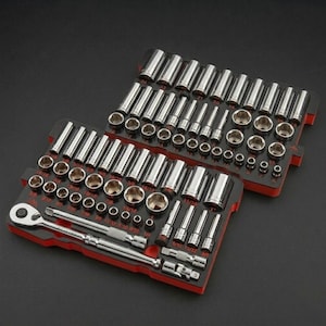 May include: A white ceramic mug with a black handle and the text "But First, Coffee" in a bold, black font. The mug is set against a blurred background, suggesting a cozy setting.