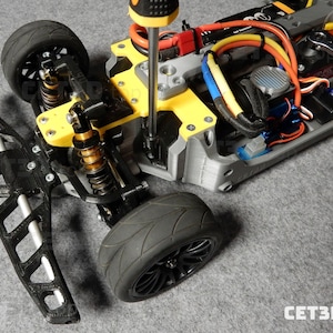 May include: A partially assembled gray and yellow RC car chassis with black tires and suspension components. A screwdriver is being used to tighten a screw on the yellow frame. The front bumper is detached. The text "CET3D.top" is visible.