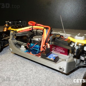May include: A detailed view of a gray and yellow remote-controlled car chassis. The car features a black tire, a blue motor, and various wires and components. The text "CET3D.top" is visible.