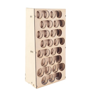 May include: A light-colored wooden paint bottle organizer with multiple circular openings. The organizer is rectangular and designed to hold small bottles, likely for art supplies or crafts. The wood has a natural finish.