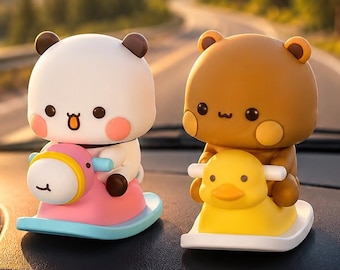 May include: Two small figurines of cartoon animals, one white and one brown, each riding a colorful rocking toy. The white animal sits on a pink and blue rocking horse, while the brown animal sits on a yellow rocking duck, both placed on a dashboard.