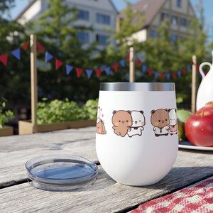 Könnte beinhalten: Ein weißer Edelstahl-Weinglas mit Deckel. Das Glas zeigt ein Cartoon-Design mit braunen Bären und weißen Pandas, die sich umarmen und Händchen halten.