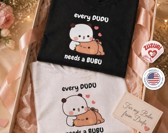 May include: Two t-shirts, one black and one white, inside a gift box. Each shirt features a cartoon panda design with the text "every DUDU needs a BUBU". A small card reads "For my Bubu from Dudu".