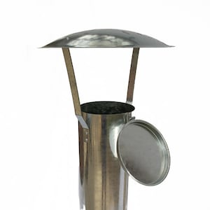May include: A silver metal chimney cap with a round lid and a rain shield. The lid is open and the cap is standing upright.