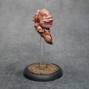Puede incluir: Una figura de criatura de fantasía de color marrón rojizo, pintada a mano. La figura está montada sobre un soporte de plástico transparente fijado a una pequeña base redonda negra con una superficie marrón texturizada.