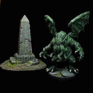 Puede incluir: Una miniatura detallada de una criatura verde alada con tentáculos y un obelisco de piedra. La criatura tiene una pose amenazante con garras afiladas y ojos rojos. El obelisco es gris con símbolos tallados.