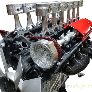 Könnte beinhalten: Nahaufnahme eines schwarzen Motors mit silbernen Kolben, einem roten Ventildeckel und einem silbernen Kettenantrieb. Der Motor ist in einem zerlegten Zustand und zeigt die inneren Komponenten.