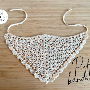 May include: Cream-colored crochet bandana with a triangular shape and a scalloped edge. The bandana has a delicate, openwork design and ties at the back of the neck. The text "PDF PATTERN ONLY!" is in a white circle. The word "Puff bandana" is written in cursive.