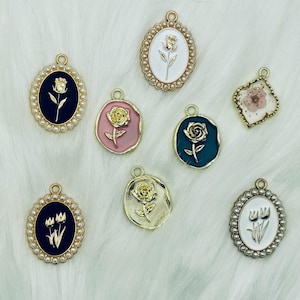 May include: Assortment of eight gold-tone charms featuring floral designs. The charms are oval-shaped with a pearl-like border and feature a variety of floral designs, including roses and tulips. The charms are perfect for adding a touch of elegance to jewelry or crafts.