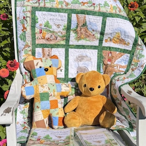 May include: A patchwork quilt featuring Winnie the Pooh illustrations and text, a flat patchwork bear, a plush golden-brown teddy bear, and two folded fabric panels. The quilt displays scenes of Christopher Robin and Friends with green borders.