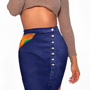 May include: A blue denim skirt with a button-up front and a colorful patterned panel on the side.