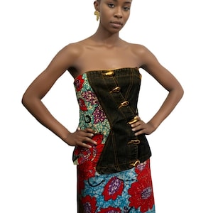 May include: A strapless top and skirt set. The top is a combination of dark denim and patterned fabric with gold-colored clasps. The skirt features a blue background with large red floral patterns. The outfit is a fusion of denim and African-inspired prints.