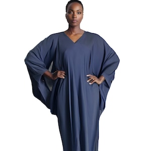 May include: A long, flowing, navy blue dress with a V-neck and wide sleeves. The dress has a loose, comfortable fit and drapes elegantly. The model is wearing the dress with their hands on their hips.