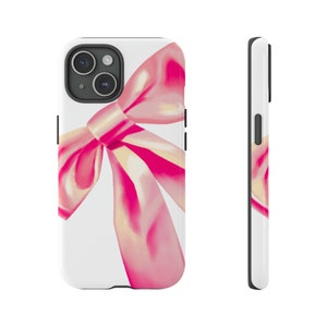 May include: A white phone case with a pink bow design. The bow is large and takes up most of the case. The phone case is for an iPhone.