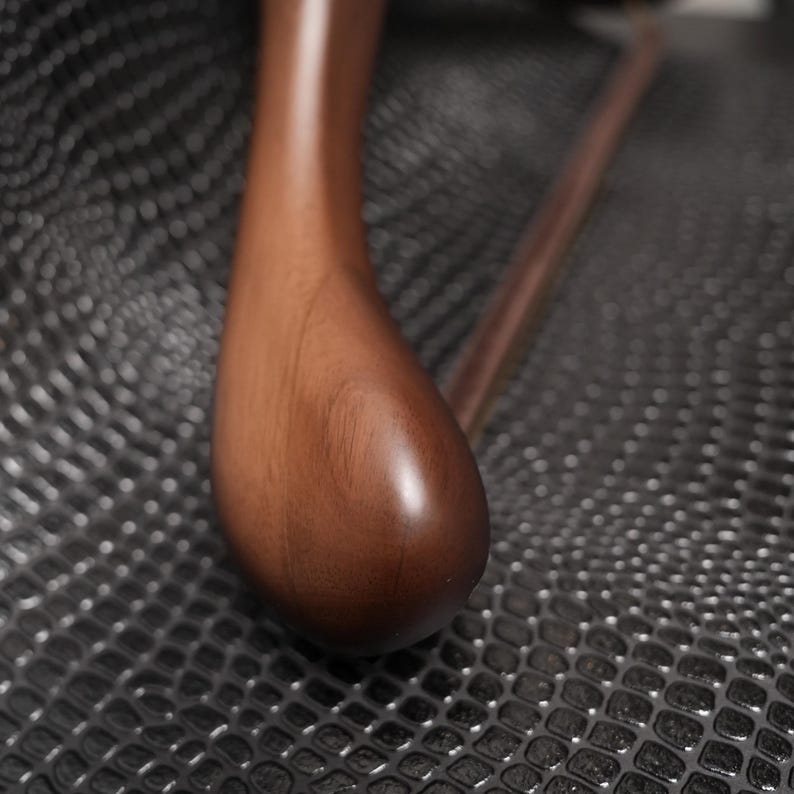 May include: A smooth, dark brown wooden clothes hanger with a curved shoulder profile and a horizontal bar, showcasing a polished finish and visible wood grain texture, designed for hanging garments with a sturdy and functional construction.