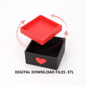 K&ouml;nnte beinhalten: Eine schwarze quadratische Box mit einem roten Herz-Ausschnitt und einem separaten roten quadratischen Deckel. Der Text "DIGITAL DOWNLOAD FILES .STL" befindet sich unten. Der Deckel befindet sich leicht &uuml;ber der Box, mit gebogenen Pfeilen darum.