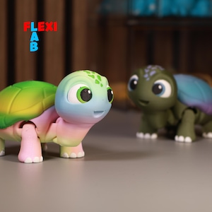 May include: Two articulated turtle figurines. One has a green and yellow shell, a blue and pink face, and pink legs. The other is green with a blue and purple shell. The word "FLEXI AB" is in red, blue, and orange.